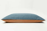 Blue cushion with brown leather trim on a white background